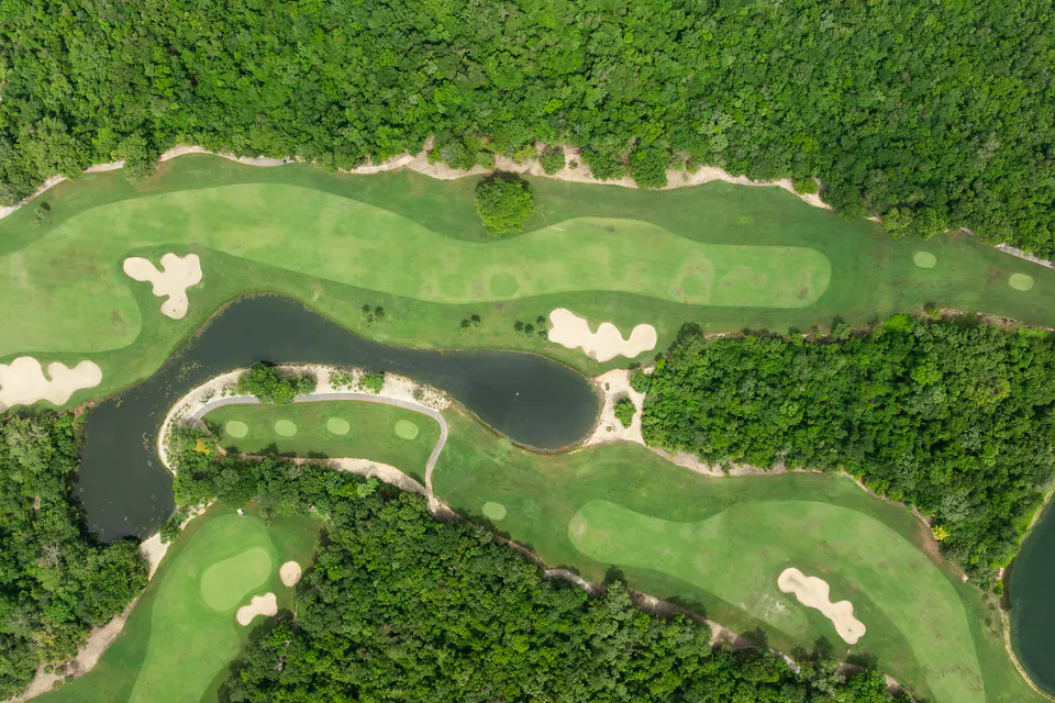 Overhead view of the 18th hole at Gran Coyote Golf: fairways, bunkers and a lake set in the jungle, in the Riviera Maya