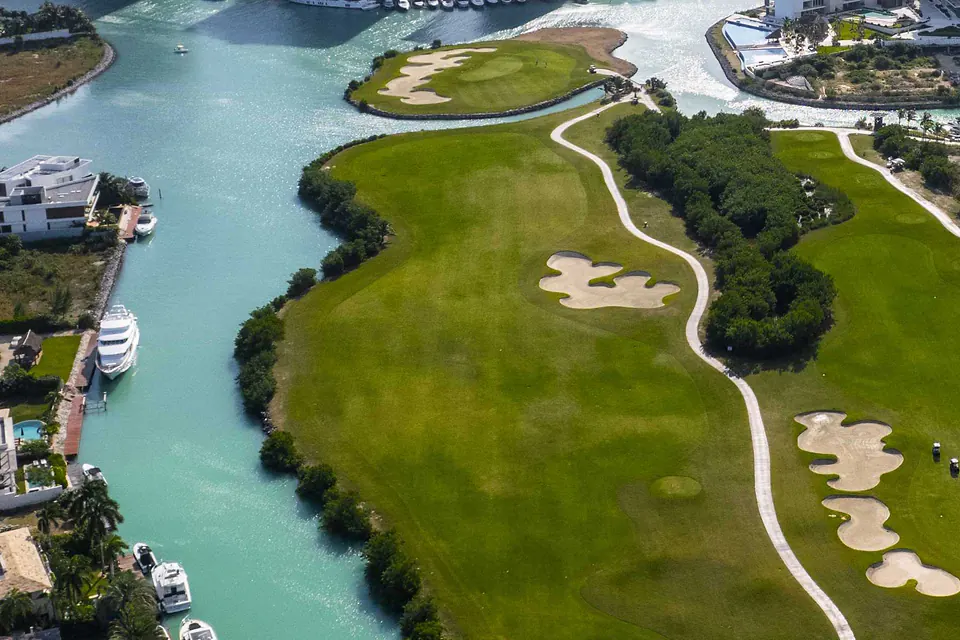 Puerto Cancún Club's fairway and island green beside the marina canals, with yachts moored alongside